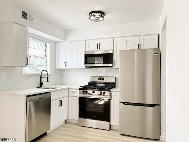 197 Riva Dr, Mansfield Twp, NJ 07840 - kitchen featuring stainless steel appliances, tasteful backsplash, light wood-style flooring, and white cabinets