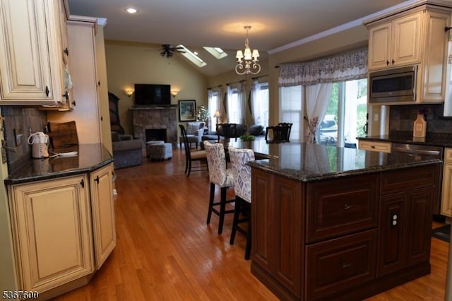 10 Links Ct, Sparta Twp, NJ 07871 - kitchen featuring stainless steel microwave, cream cabinets, a fireplace, decorative backsplash, and open floor plan