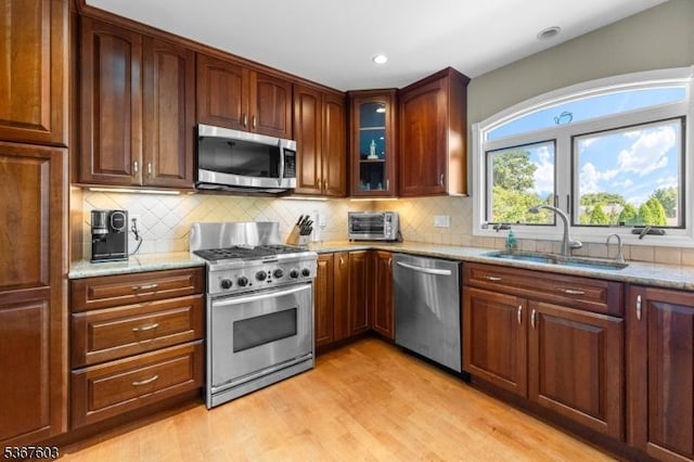 26 Ditmars Cir, Hillsborough Twp, NJ 08844 - kitchen with appliances with stainless steel finishes, light stone countertops, light wood-type flooring, tasteful backsplash, and glass insert cabinets