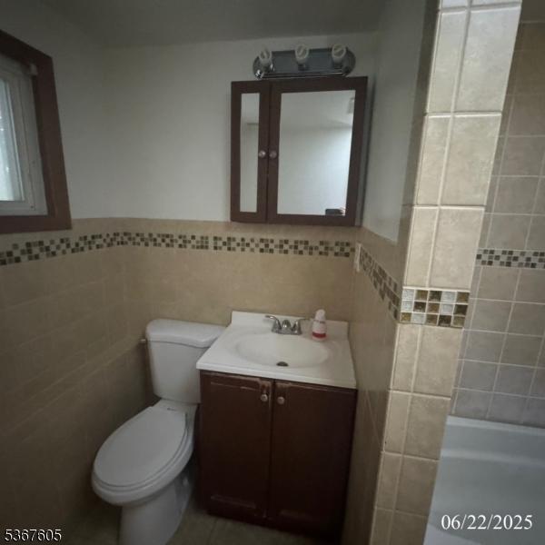 35 Eastern Pkwy, Hillside Twp, NJ 07205 - bathroom with tile walls, vanity, a tub, and wainscoting
