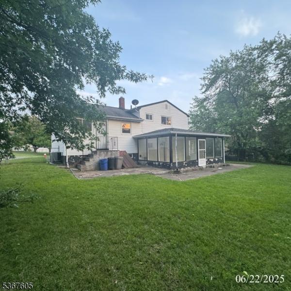35 Eastern Pkwy, Hillside Twp, NJ 07205 - back of house with a sunroom, a lawn, and a chimney