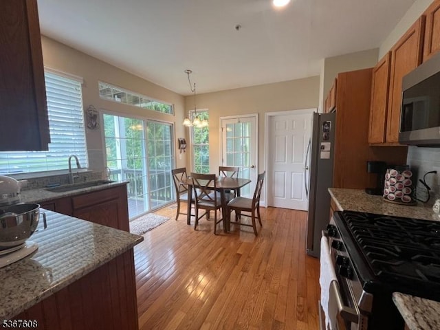 1002 Deerhaven Ter, Lopatcong Twp, NJ 08886 - kitchen with appliances with stainless steel finishes, brown cabinetry, light wood-style flooring, and decorative light fixtures