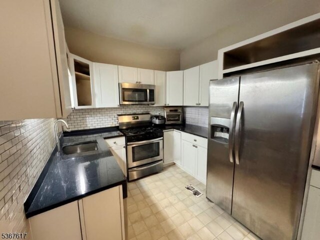 8619 Brittany Dr, Wayne Twp, NJ 07470 - kitchen featuring stainless steel appliances, white cabinetry, backsplash, dark countertops, and light flooring