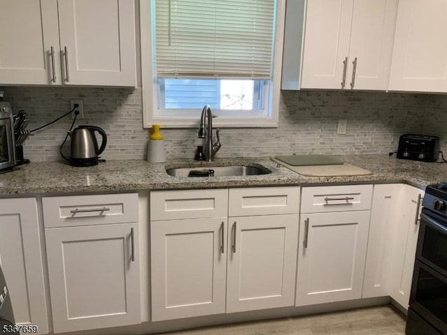 116 Mapes Ave Unit 3, Newark City, NJ 07112 - kitchen featuring white cabinetry, tasteful backsplash, light stone countertops, and range