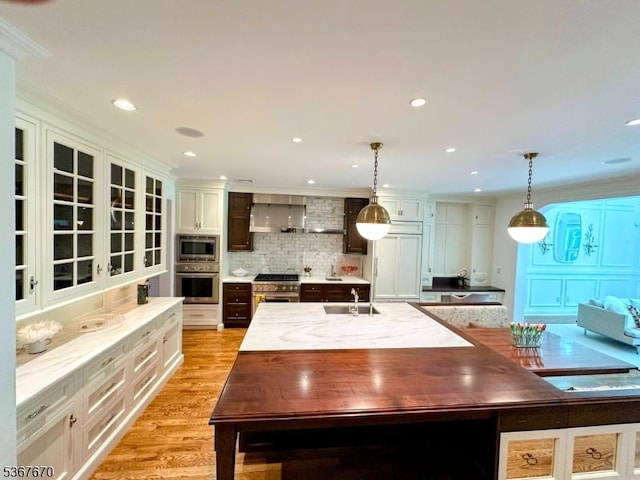 15 Poplar Ln, Chatham Twp, NJ 07928 - kitchen featuring built in appliances, wall chimney exhaust hood, backsplash, a center island with sink, and hanging light fixtures