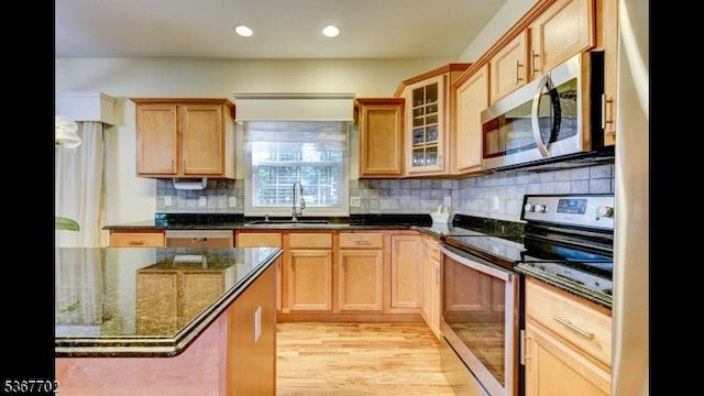 4 Lindsay Ln, Sparta Twp, NJ 07871 - kitchen featuring stainless steel appliances, dark stone counters, light wood-style floors, decorative backsplash, and glass insert cabinets