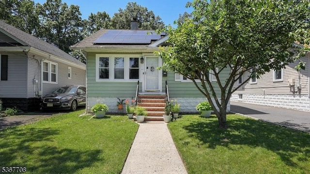 114 Oakley St, Roselle Boro, NJ 07203 - view of front facade featuring solar panels, a front lawn, entry steps, and a chimney