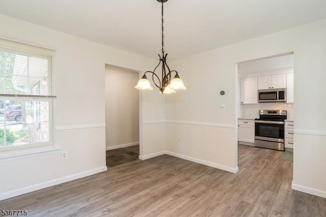 255 Glastonbury Ln, Franklin Twp, NJ 08873 - unfurnished dining area featuring a chandelier, healthy amount of natural light, and wood finished floors