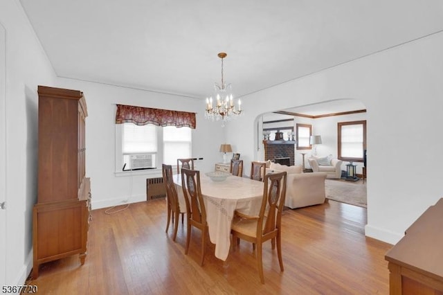 74 Elm Rd, Caldwell Boro Twp, NJ 07006 - dining space with radiator, arched walkways, light wood-style floors, and a brick fireplace