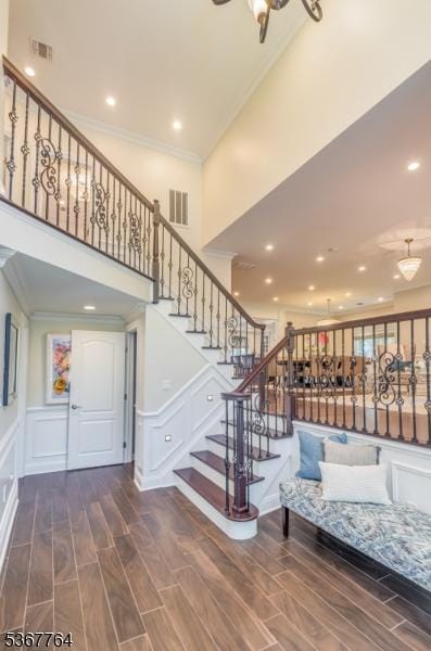 106 Woodbine Cir, New Providence Boro, NJ 07974 - stairs featuring crown molding, a decorative wall, wood finished floors, a towering ceiling, and a wainscoted wall