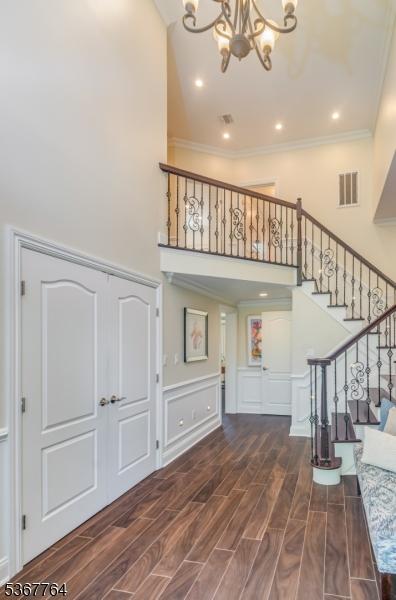 106 Woodbine Cir, New Providence Boro, NJ 07974 - foyer with a high ceiling, a chandelier, stairway, crown molding, and wood finished floors