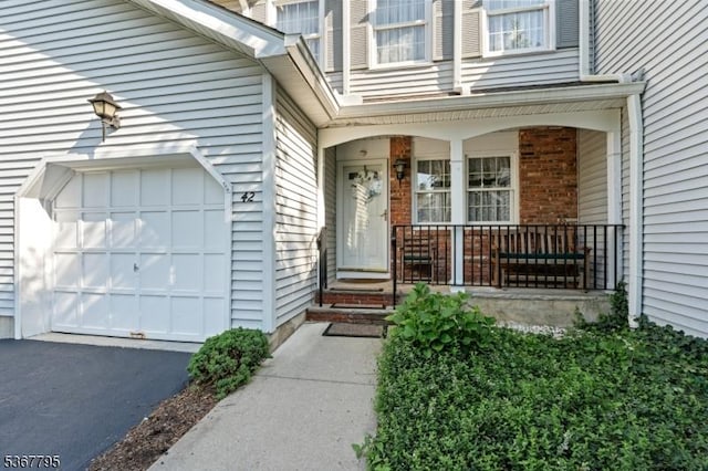 42 Carriage Ln, Sparta Twp, NJ 07871 - view of exterior entry with covered porch, brick siding, and driveway