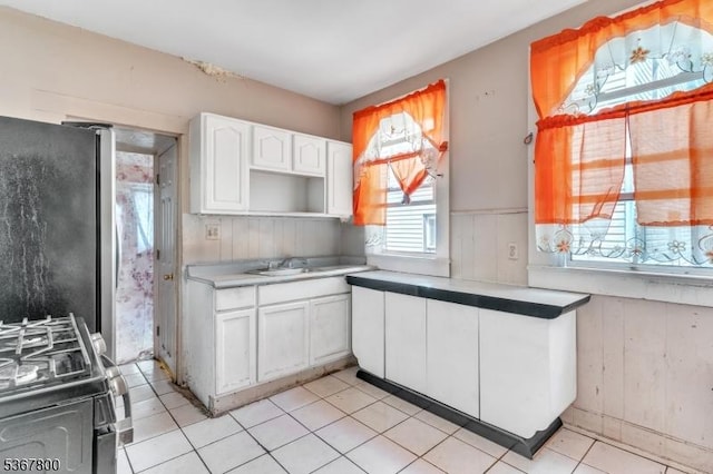 1705 Essex St, Rahway City, NJ 07065 - kitchen featuring gas range, freestanding refrigerator, white cabinetry, a wainscoted wall, and wooden walls