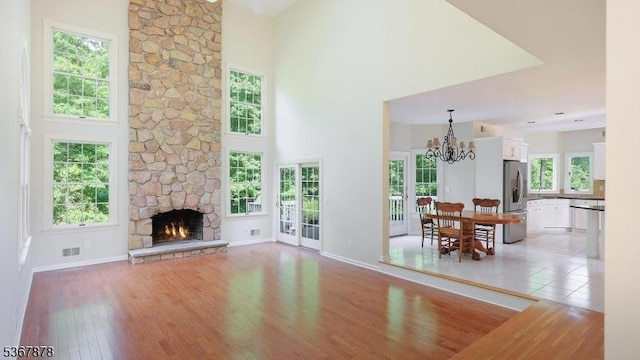 64 Sneider Rd, Warren Twp, NJ 07059 - living room featuring a chandelier, a towering ceiling, light wood-type flooring, and a stone fireplace