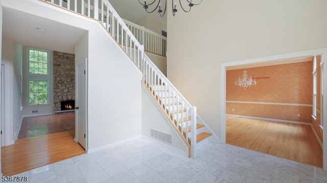 64 Sneider Rd, Warren Twp, NJ 07059 - stairway featuring a chandelier, a towering ceiling, a fireplace, and wood finished floors