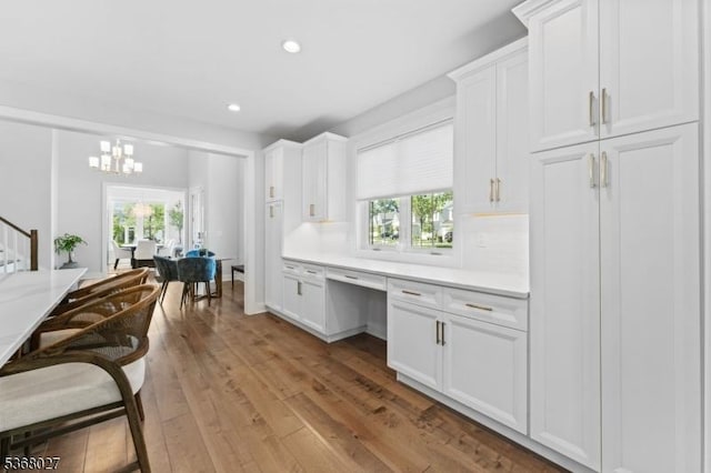 28 Peacock Ln Unit 28, Berkeley Heights Twp, NJ 07922 - kitchen with built in desk, light countertops, light wood-style floors, white cabinets, and a chandelier