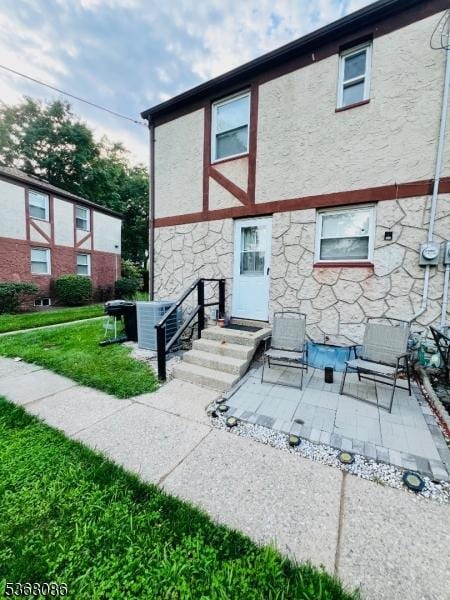 185 High St, Metuchen Boro, NJ 08840 - rear view of house with stone siding, a yard, and stucco siding
