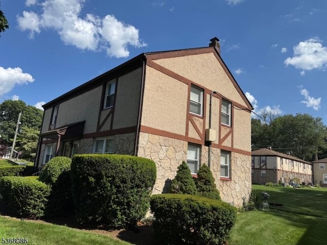 185 High St, Metuchen Boro, NJ 08840 - view of side of home featuring stone siding, stucco siding, a chimney, and a yard