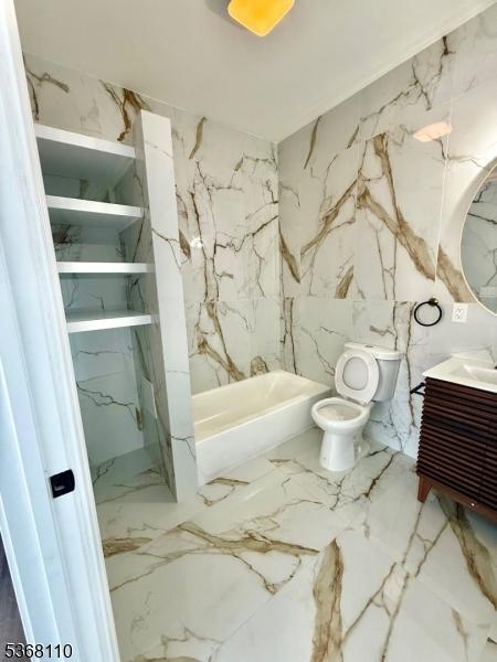 109 Fulton St, Elizabeth City, NJ 07206 - full bath with vanity, marble tiled floors, a bath, and stone wall