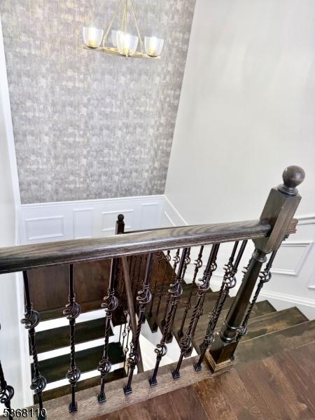 109 Fulton St, Elizabeth City, NJ 07206 - stairs featuring wood finished floors, a decorative wall, a wainscoted wall, and a chandelier