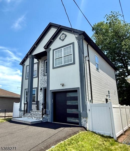 47 Bird Ave, Woodbridge Twp, NJ 08830 - view of front facade with stone siding, an attached garage, and asphalt driveway
