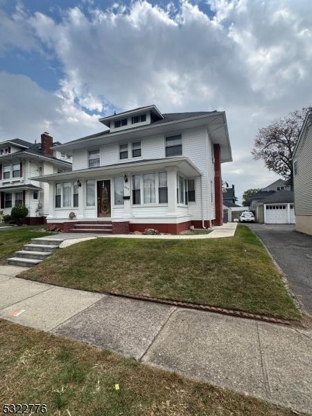393 E 38th St, Paterson City, NJ 07504 - american foursquare style home featuring a front yard, a garage, and asphalt driveway