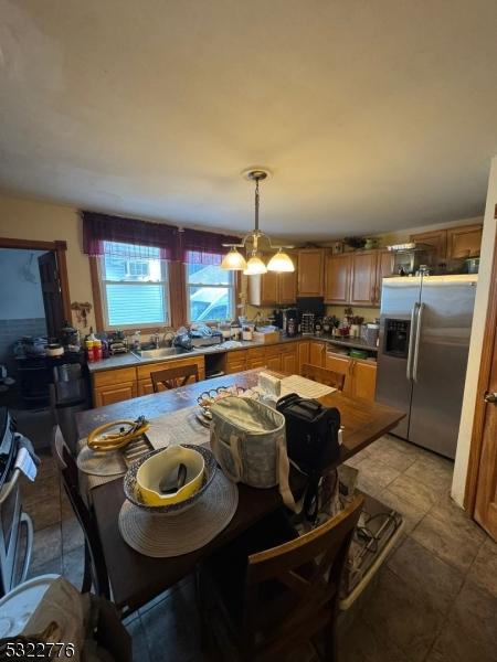 393 E 38th St, Paterson City, NJ 07504 - kitchen featuring stainless steel refrigerator with ice dispenser, hanging light fixtures, stove, and brown cabinetry