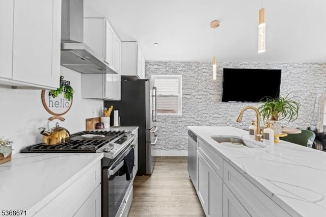 1465 E 2nd St, Plainfield City, NJ 07062 - kitchen with wall chimney range hood, stainless steel appliances, light wood finished floors, light stone countertops, and white cabinets