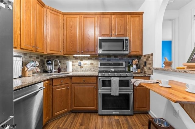 301 Rainbow Way Unit 301, Lopatcong Twp, NJ 08865 - kitchen with appliances with stainless steel finishes, dark wood-style flooring, light stone countertops, decorative backsplash, and brown cabinetry