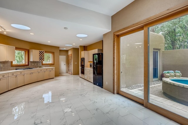 kitchen featuring tasteful backsplash, light brown cabinets, light tile flooring, and black appliances