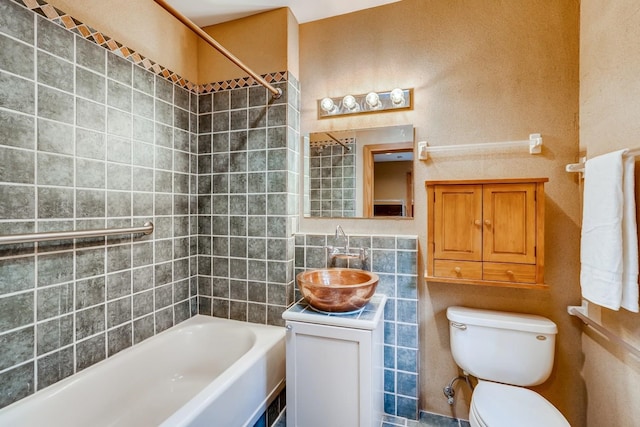 full bathroom with vanity, tiled shower / bath combo, toilet, and tile walls