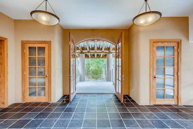 entryway with dark tile floors and french doors