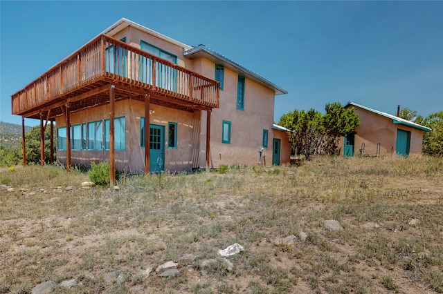 rear view of property featuring stucco siding and a deck