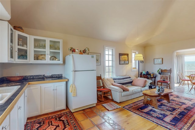 kitchen featuring a wealth of natural light, glass insert cabinets, white cabinets, and freestanding refrigerator