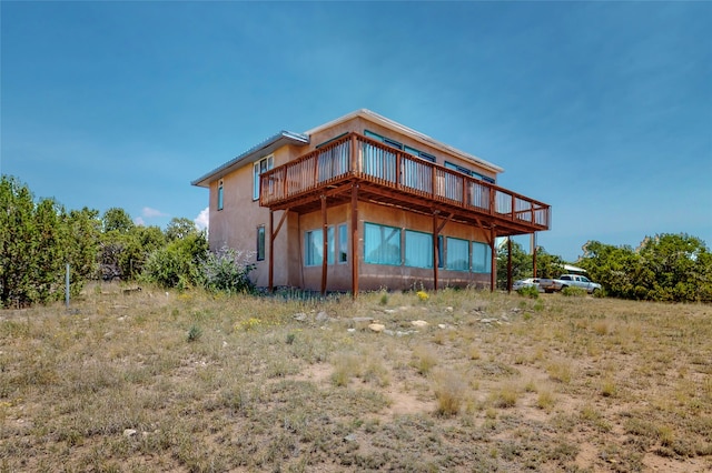 back of house with stucco siding and a wooden deck