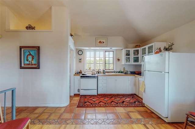 kitchen with a sink, white cabinetry, white appliances, glass insert cabinets, and lofted ceiling