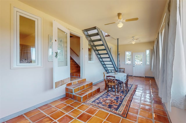 interior space with stairs, a ceiling fan, and baseboards