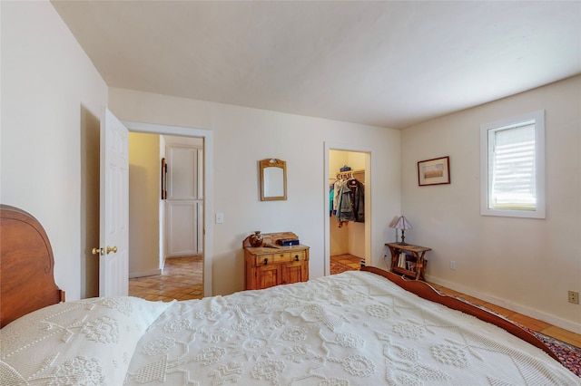 bedroom featuring a walk in closet, baseboards, and a closet