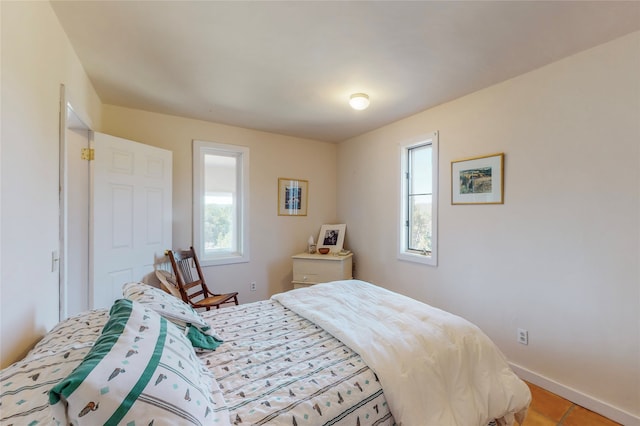 bedroom with multiple windows, baseboards, and light tile patterned floors