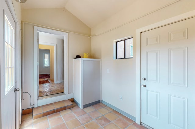 foyer with light tile patterned floors, baseboards, plenty of natural light, and vaulted ceiling