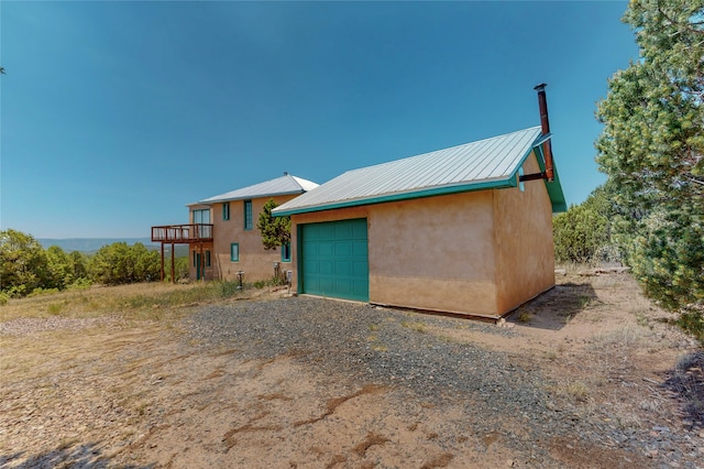 view of front facade featuring stucco siding, metal roof, an outdoor structure, a garage, and driveway