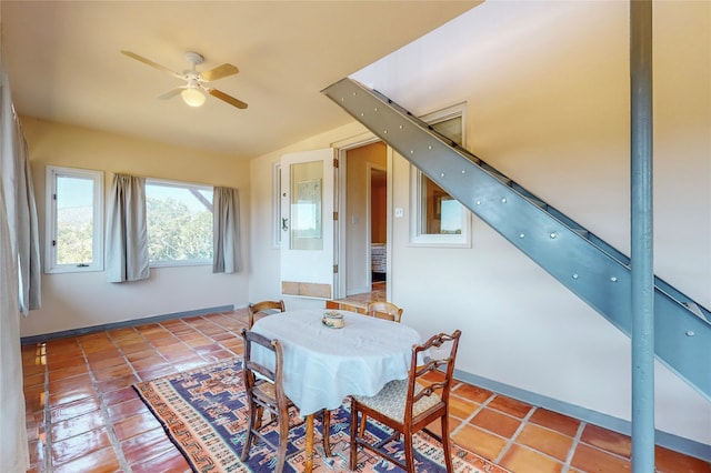 tiled dining space with baseboards, lofted ceiling, a ceiling fan, and stairway