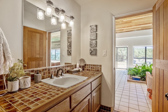 bathroom featuring a healthy amount of sunlight, decorative backsplash, tile patterned floors, and vanity