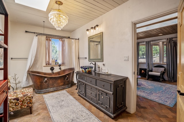 bathroom with a healthy amount of sunlight, a tub, vanity, and a chandelier