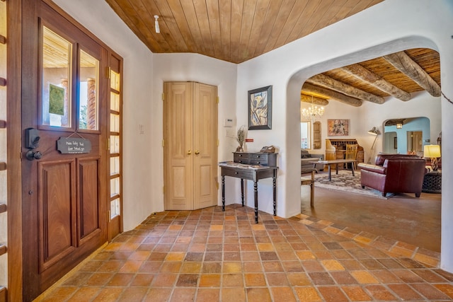 foyer entrance featuring beamed ceiling, an inviting chandelier, and wooden ceiling