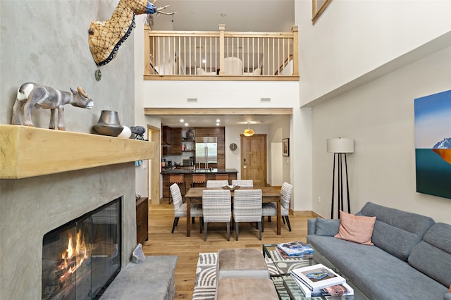 living room featuring a high ceiling, light hardwood / wood-style flooring, and a premium fireplace