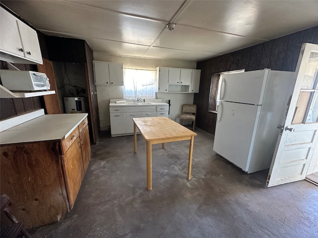 kitchen featuring white refrigerator, sink, and white cabinetry