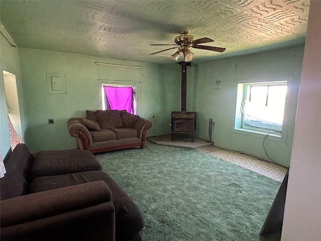 living room with ceiling fan, carpet flooring, and a wood stove