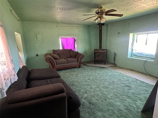 carpeted living room featuring ceiling fan and a wood stove