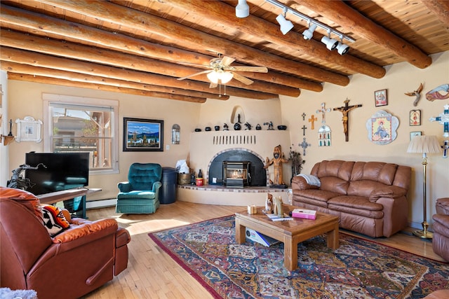 living room featuring beam ceiling, a wood stove, wooden ceiling, a baseboard radiator, and light hardwood / wood-style floors